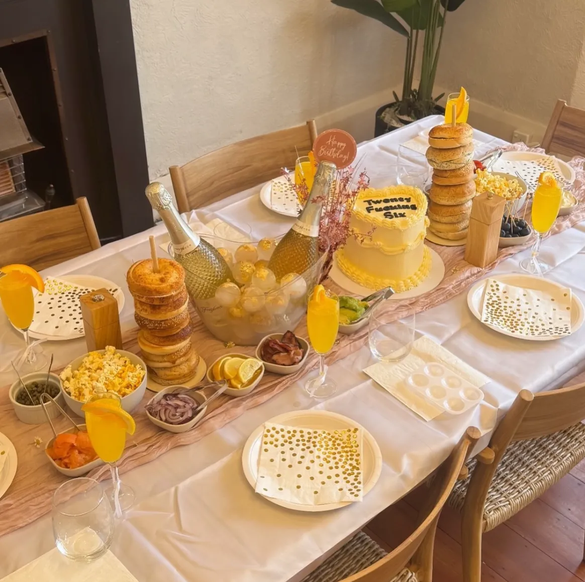 Styled birthday table with cake, drinks, tableware, and decor.