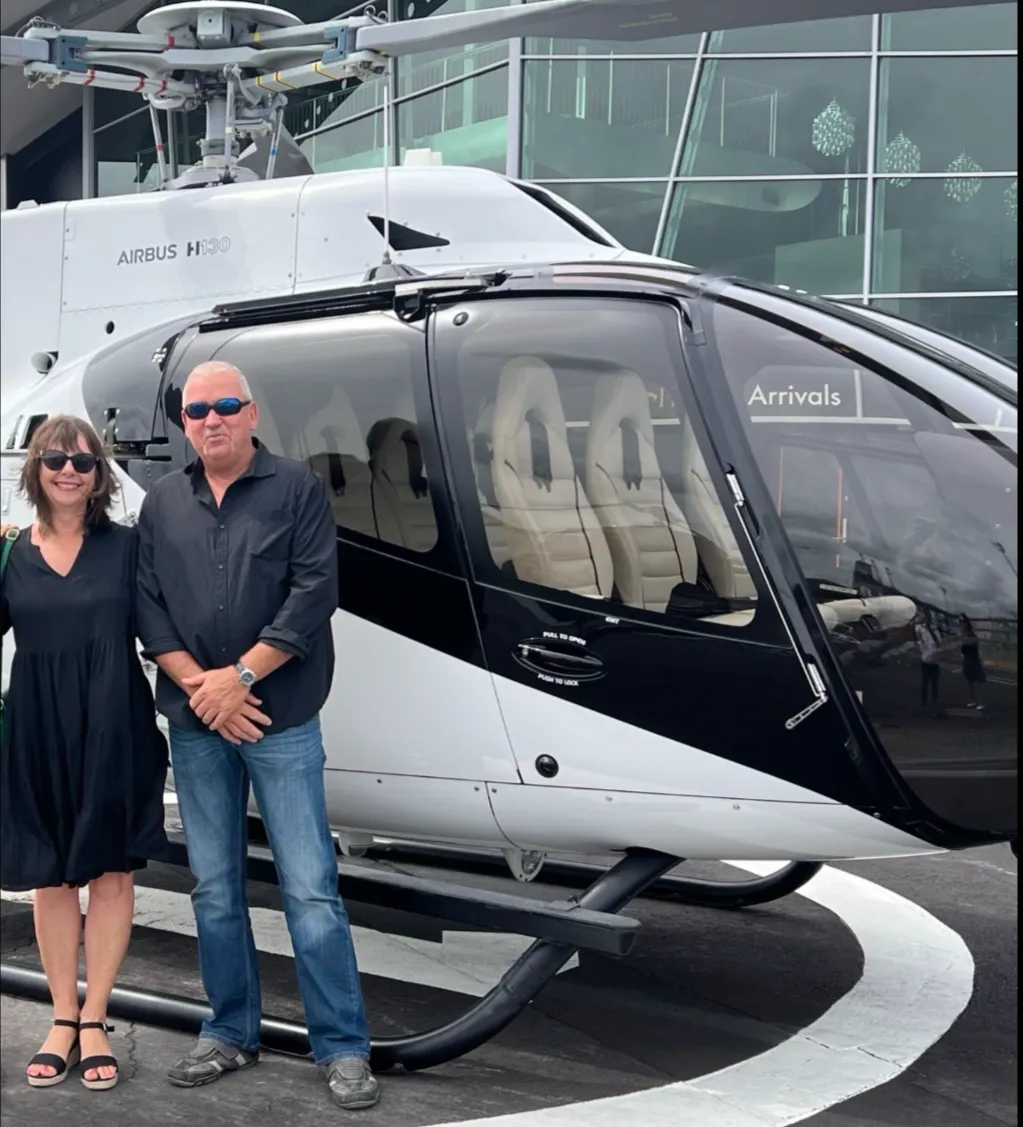 Two guests standing beside a helicopter during an event experience.