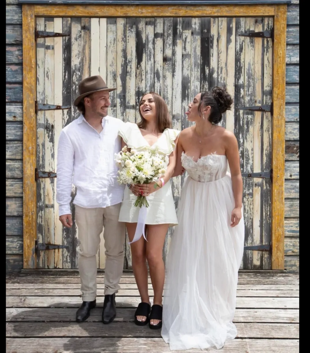 Three people celebrating at an Auckland event with a bouquet.